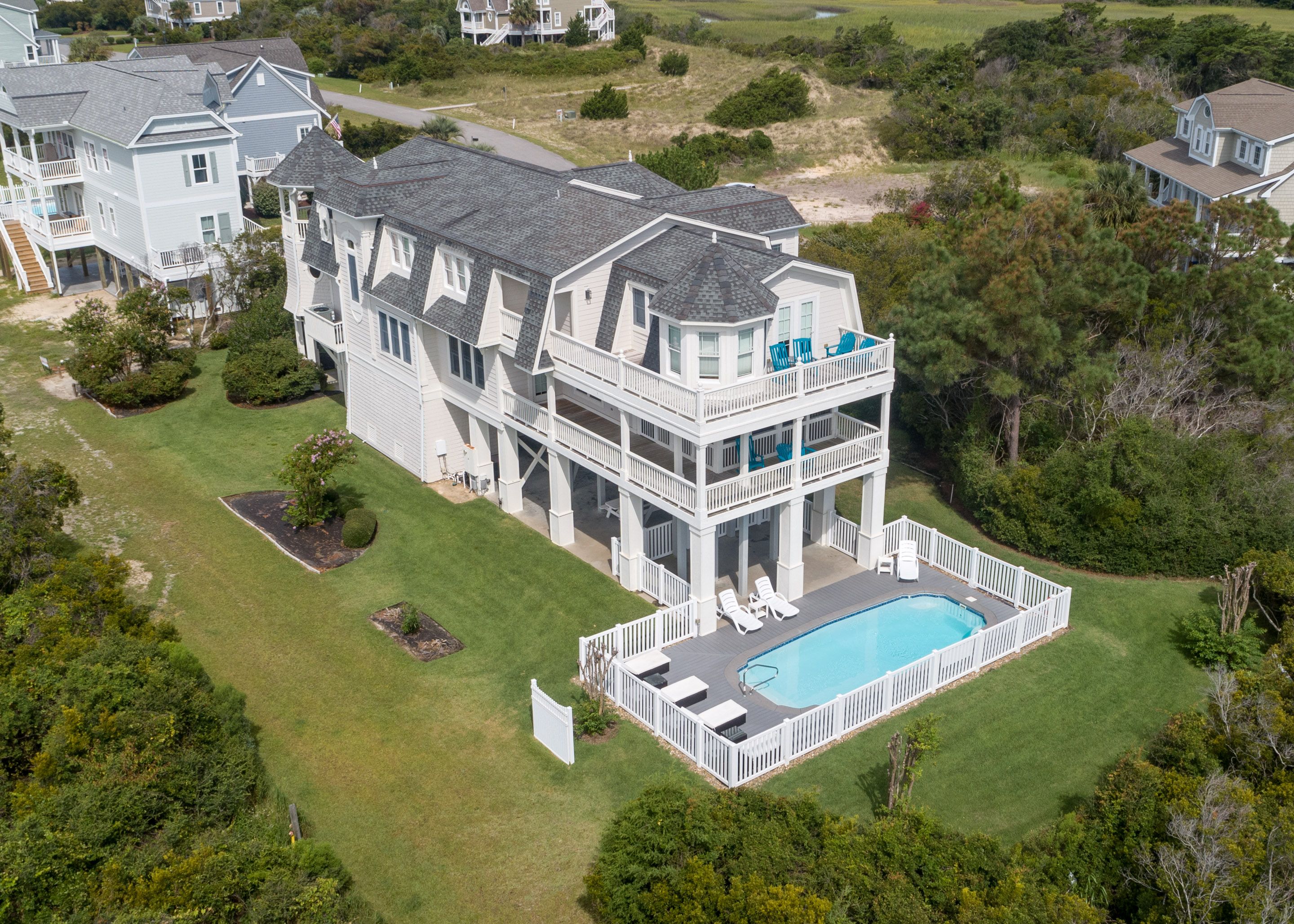 Large white home in Holden Beach with private pool surrounded with white fence