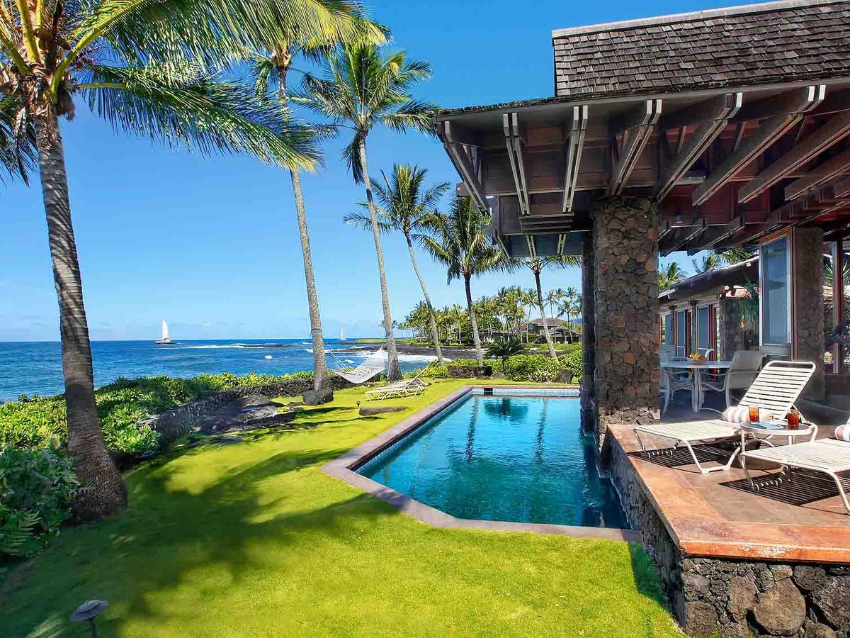 two lounge chairs on porch with pool overlooking ocean