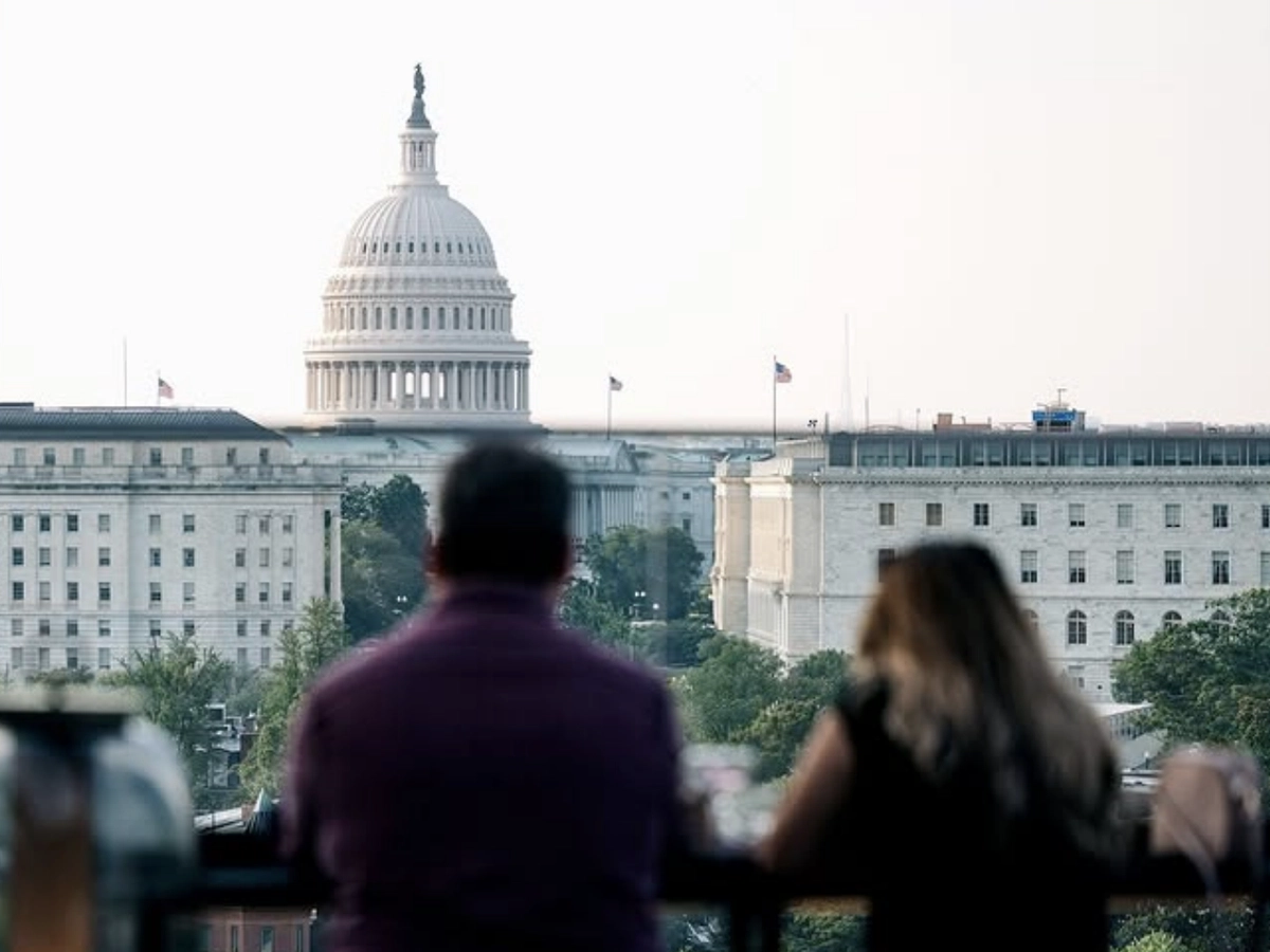 Two people on a rooftop terrace overlooking the U.S. Capitol building in Washington, D.C.