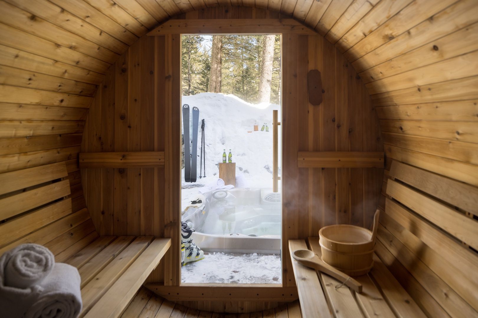 Interior of sauna with open door overlooking steamy hot tub and snow