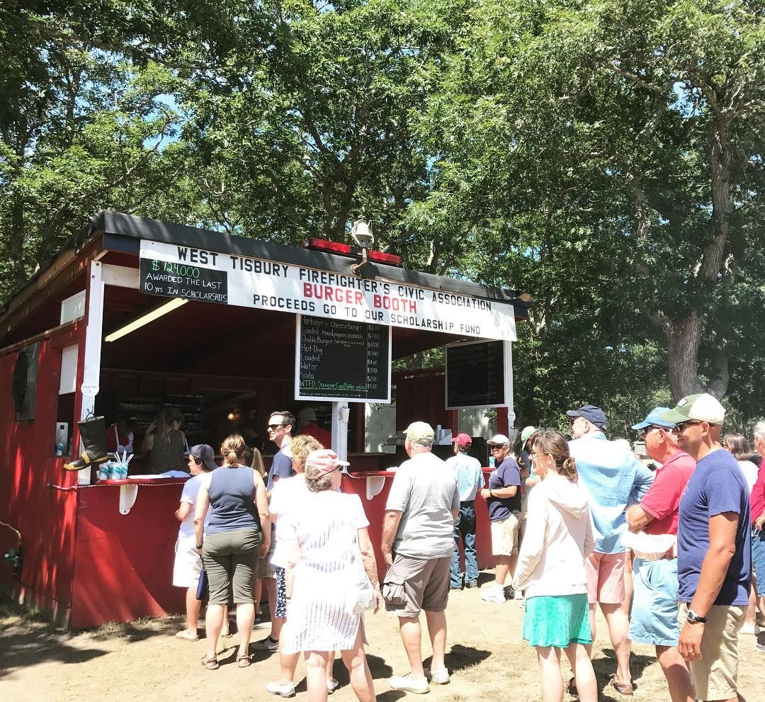 Visitors line up at the West Tisbury Firefighters Civic Association Burger Booth during the Martha’s Vineyard Agricultural Fair. The summer sun, friendly chatter, and the smell of grilled food create a classic fairground experience for locals and visitors alike.