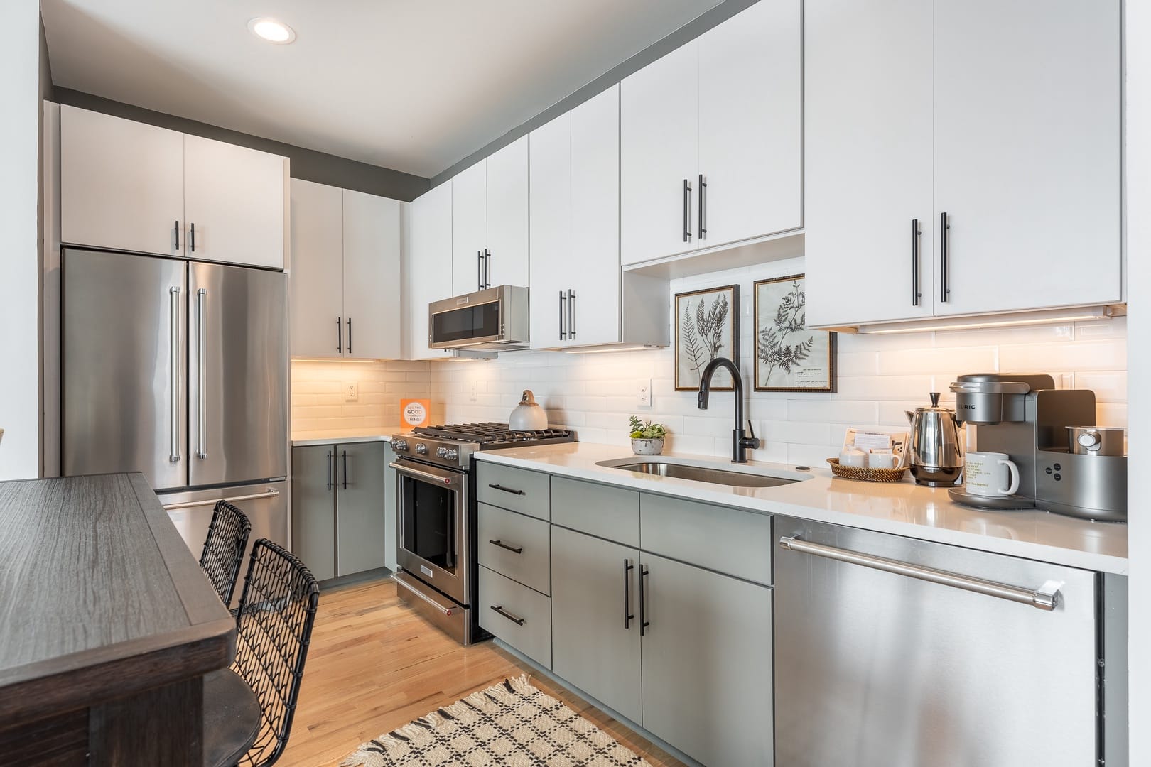 A sleek modern kitchen with stainless steel appliances, white cabinetry, subway tile backsplash, and a cozy coffee station on the counter.