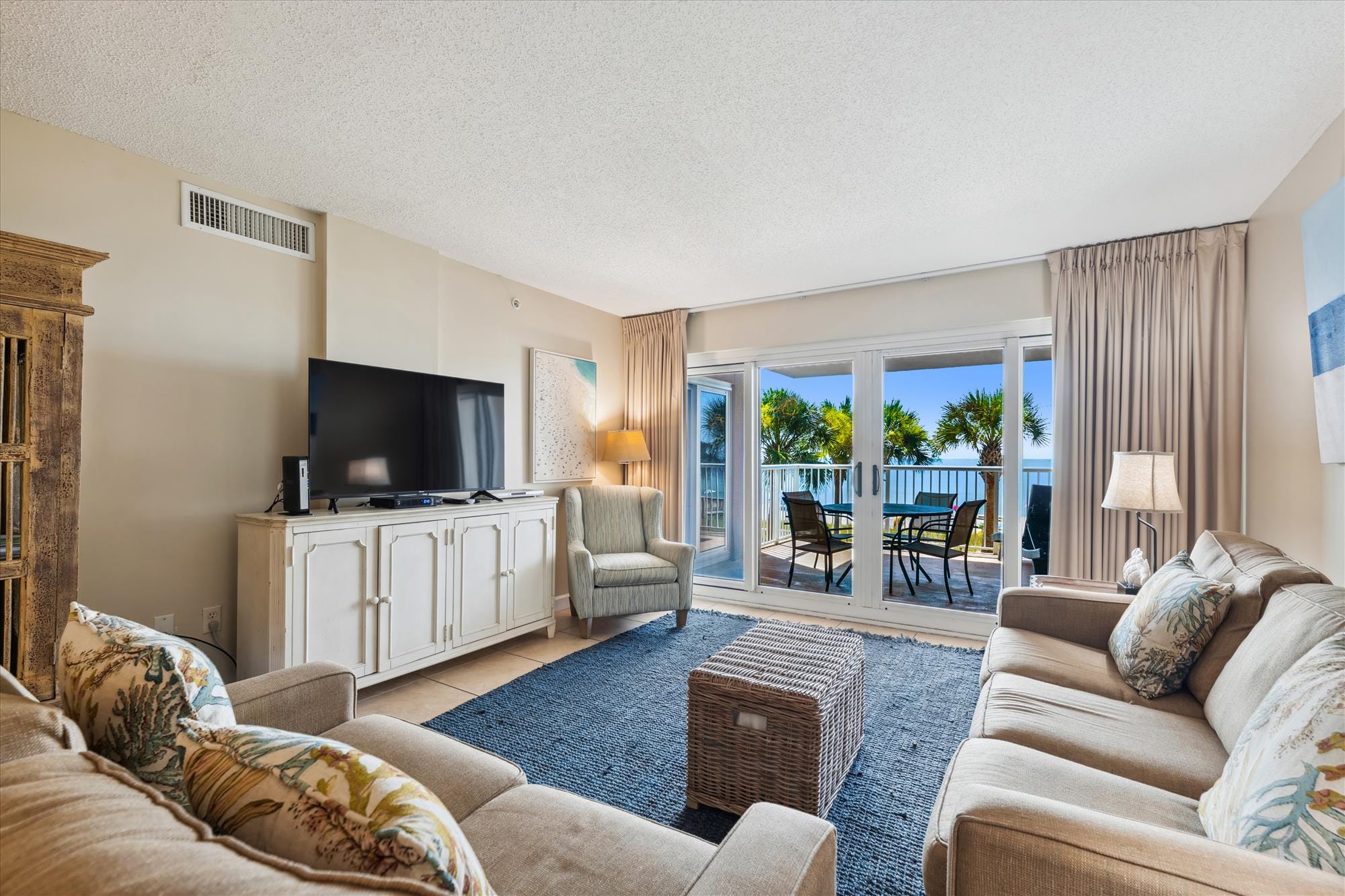 A shaded balcony with palm-tree views invites you to unwind while watching gentle waves roll onto the shore. The setup is simple and peaceful, perfect for morning coffee or sunset watching.