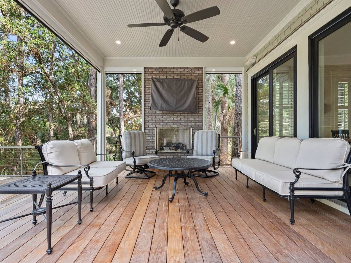 Beautiful screened-in porch with cushioned seating and a cozy fireplace, perfect for relaxing among the trees. This outdoor space is ideal for morning coffee or evening cocktails in a peaceful setting.