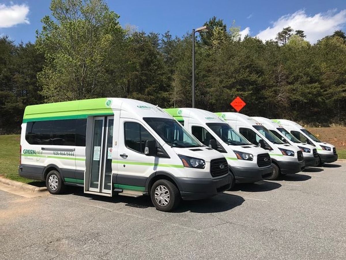 Greenway Public Transit vans line up under a clear sky, ready to shuttle riders across Western North Carolina. This eco-friendly service makes traveling around the mountains simple and stress-free.