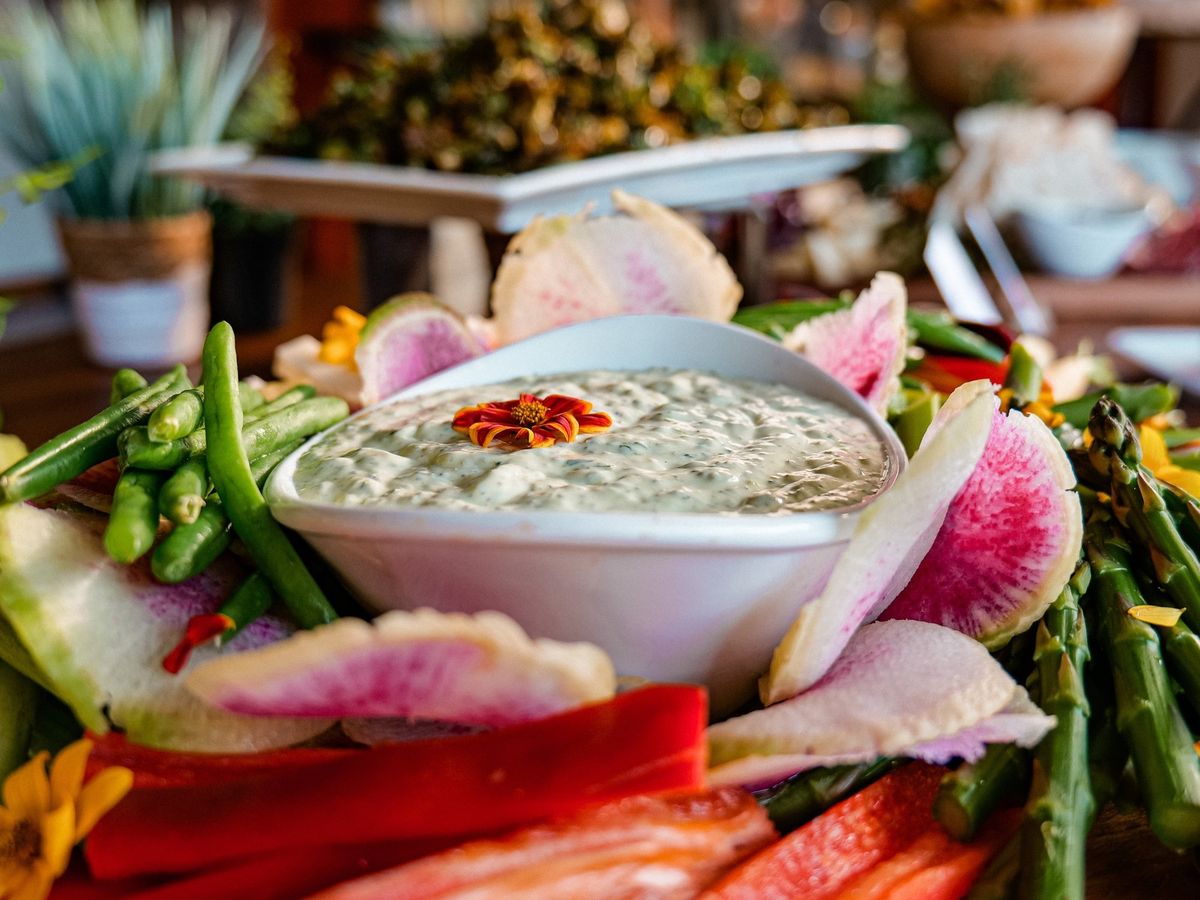 A fresh vegetable platter with dip, surrounded by colorful radishes, peppers, and asparagus at The Herb Box. This vibrant spread showcases the restaurant’s focus on seasonal, farm-to-table dishes.