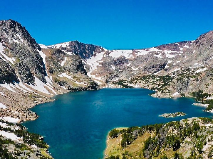 Crystal-clear Glacier Lake sits high in Montana’s mountains, surrounded by rugged peaks and snow patches. A must-see destination for hikers.