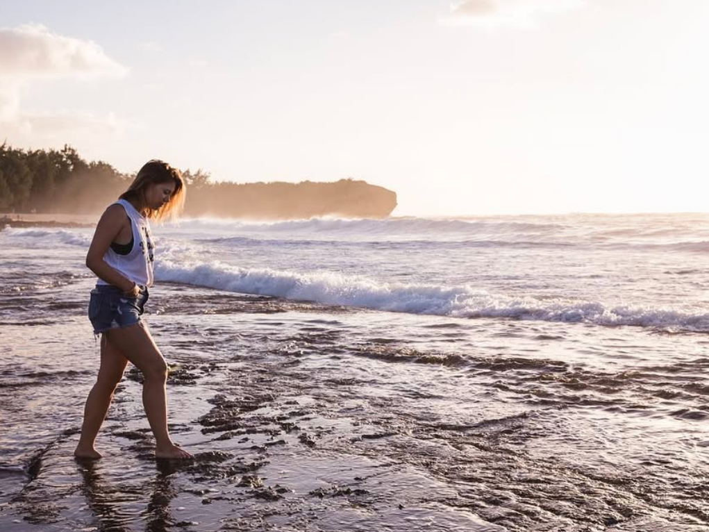 Woman walking along beach with  shorts and t shirt on