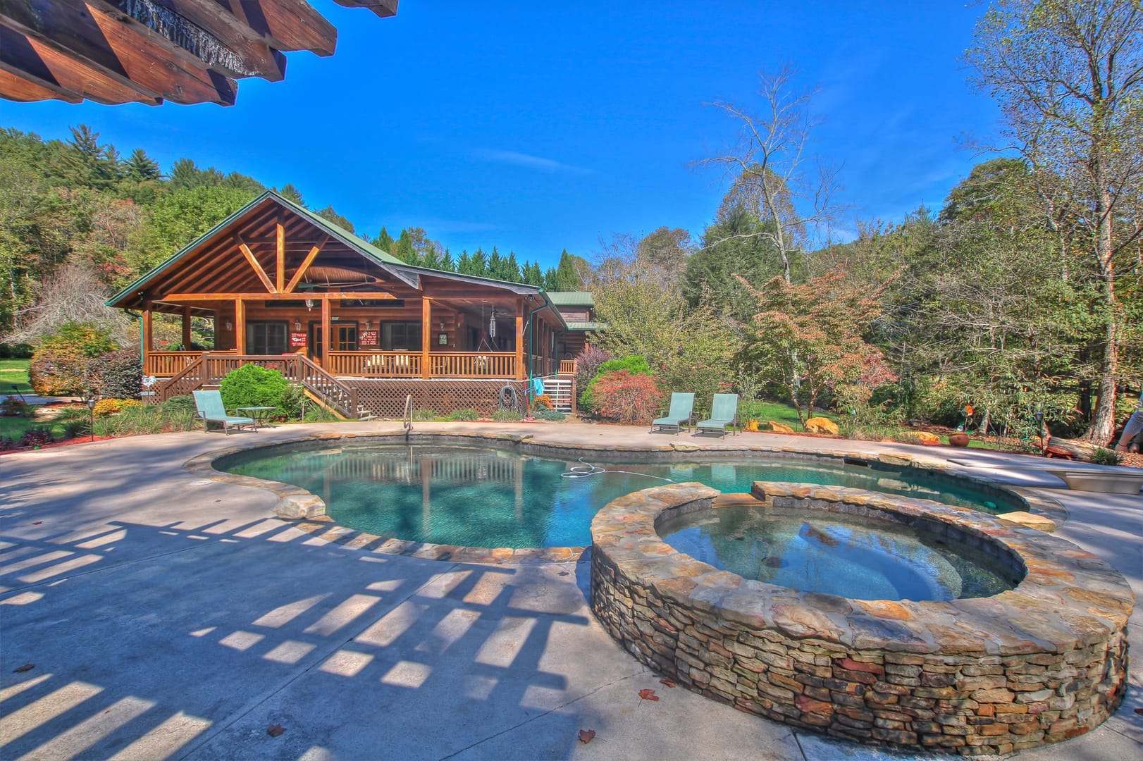 A rustic cabin overlooks a lagoon-style pool and round stone hot tub. The scene blends outdoor living with comfort, giving guests space to relax their own way.