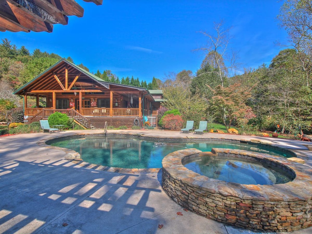 A rustic cabin overlooks a lagoon-style pool and round stone hot tub. The scene blends outdoor living with comfort, giving guests space to relax their own way.