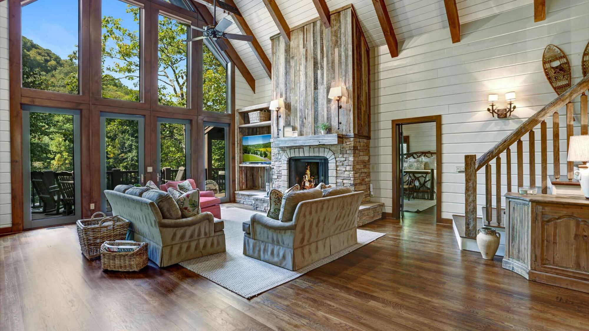 A charming cabin deck overlooks a gentle stream flowing through a quiet wooded setting. Surrounded by tall trees and greenery, this lakefront retreat feels private and peaceful. It’s an ideal escape for nature lovers who want to unwind near the water.