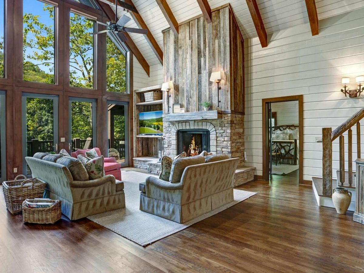 A charming cabin deck overlooks a gentle stream flowing through a quiet wooded setting. Surrounded by tall trees and greenery, this lakefront retreat feels private and peaceful. It’s an ideal escape for nature lovers who want to unwind near the water.