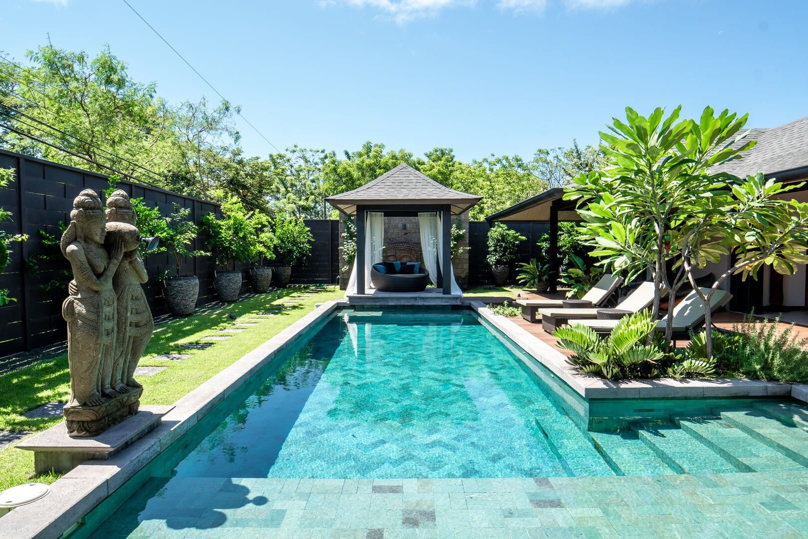 Soul House features a private tropical swimming pool surrounded by lush greenery, sun loungers, and a shaded poolside cabana. The peaceful outdoor space offers plenty of privacy for a relaxing stay in Tamarindo, Costa Rica.