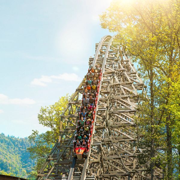 The Lightning Rod roller coaster speeds down a steep wooden track at Dollywood under a glowing sun. Set against the Smoky Mountains, this high-speed ride delivers non-stop thrills and scenic views.