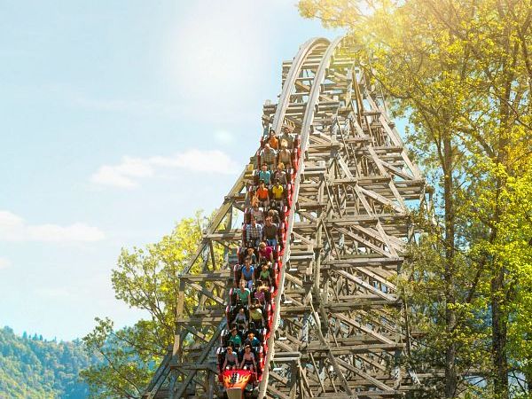 The Lightning Rod roller coaster speeds down a steep wooden track at Dollywood under a glowing sun. Set against the Smoky Mountains, this high-speed ride delivers non-stop thrills and scenic views.