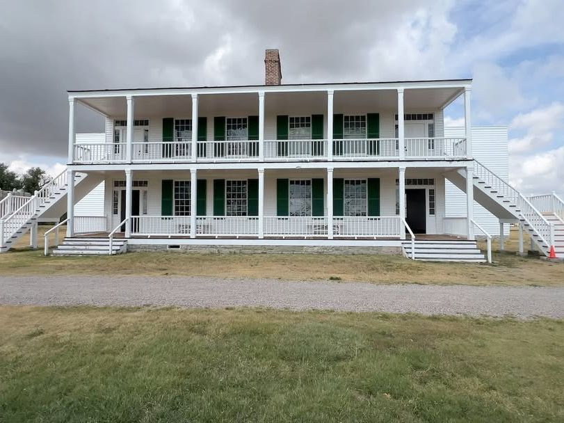 The restored white wooden barracks at Fort Laramie stand under a dramatic cloudy sky. Once a key outpost in the 1800s, this historic site gives a glimpse into Wyoming’s frontier past.