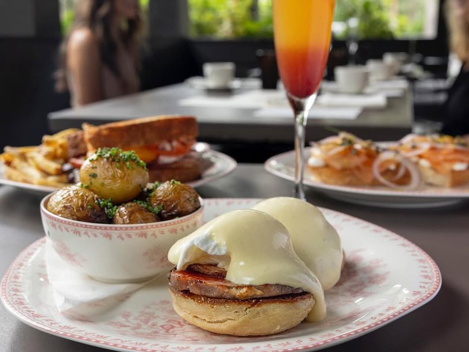 A cozy brunch spread at Woodside features eggs benedict, crispy potatoes, a mimosa, and smoked salmon bagels. This relaxed setup is perfect for a slow morning with friends.