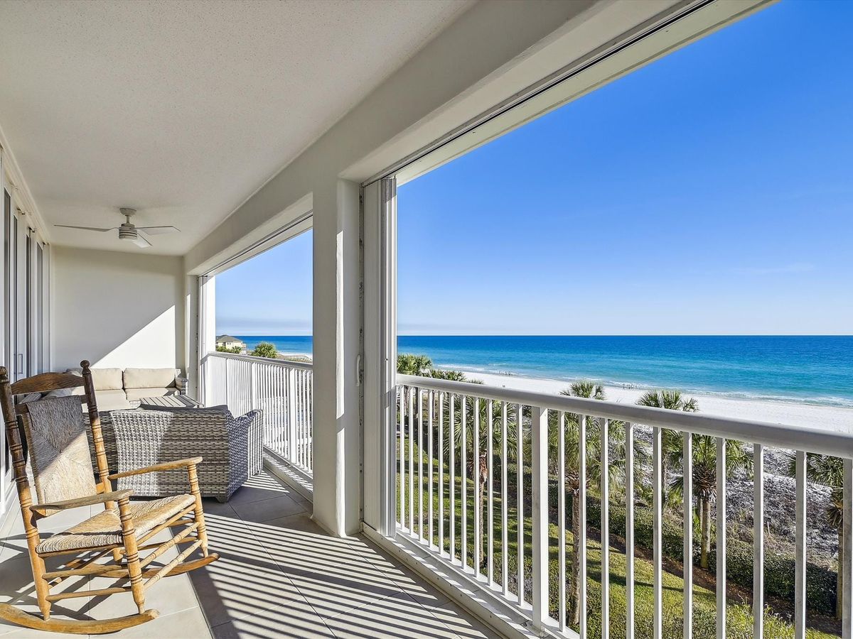 A relaxing balcony view from a Destin beach house, featuring a rocking chair, cozy seating, and sweeping views of the Gulf’s turquoise water and white sand. Ideal for a serene coastal stay.