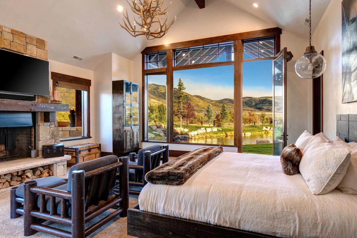 Bedroom of a vacation rental in Park City, Utah - with large, open window overlooking nature and a pond