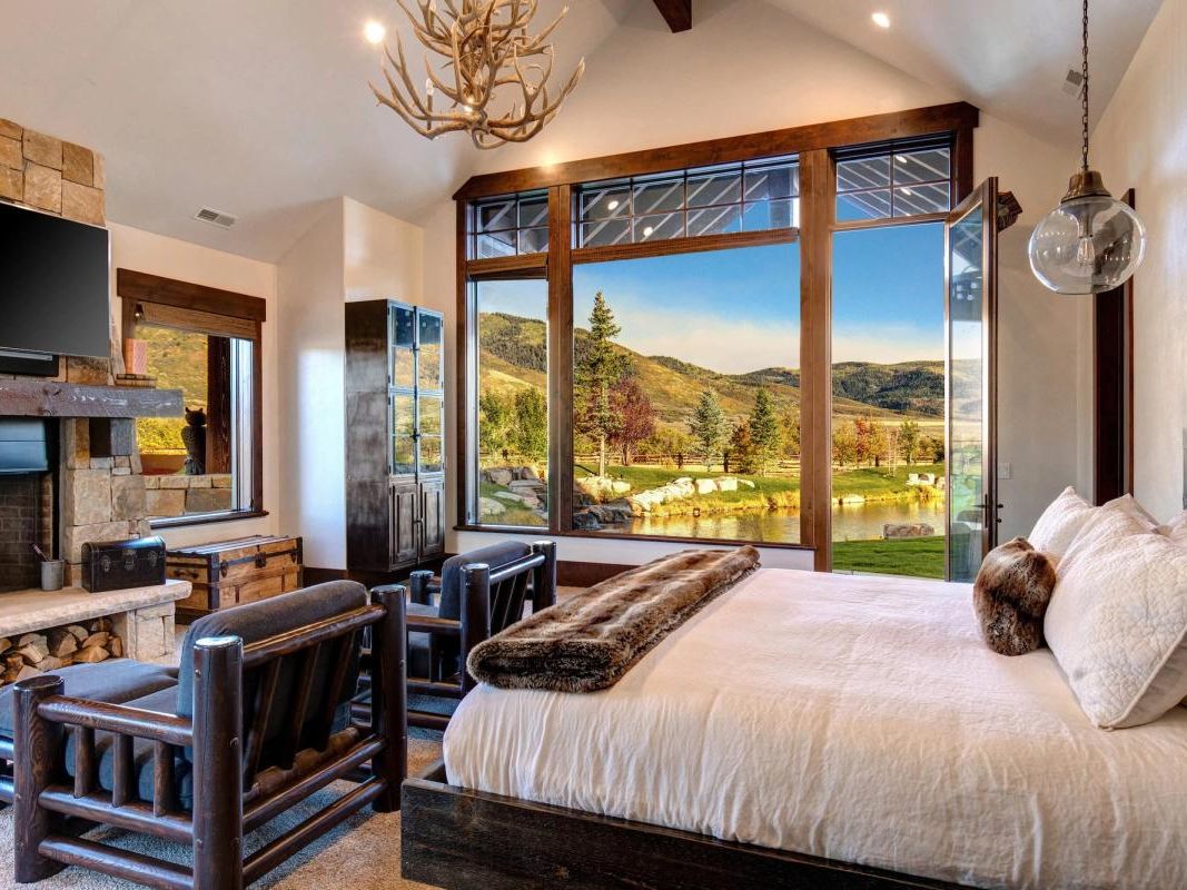 Bedroom of a vacation rental in Park City, Utah - with large, open window overlooking nature and a pond