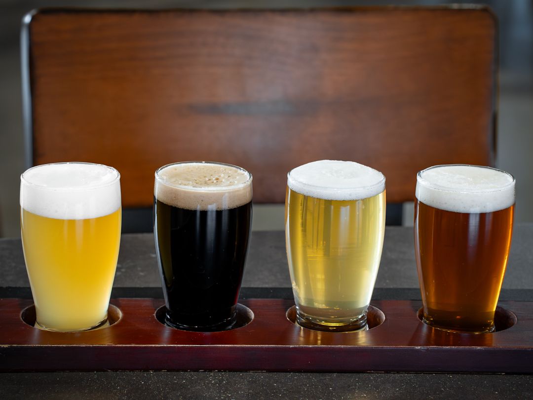 A flight of four beers—light to dark—rests on a tasting board in Asheville. It’s a great stop for beer lovers who want to sample creative flavors in a cool, rustic setting.