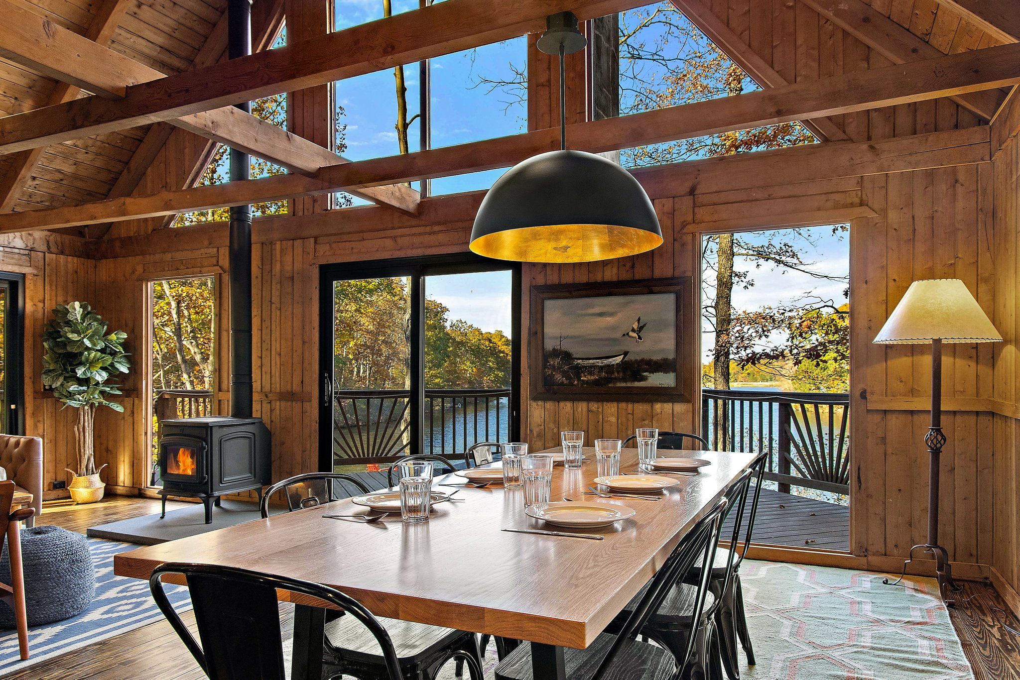 Interior of dining room with windows overlooking the nature and lake with cozy fireplace indoors