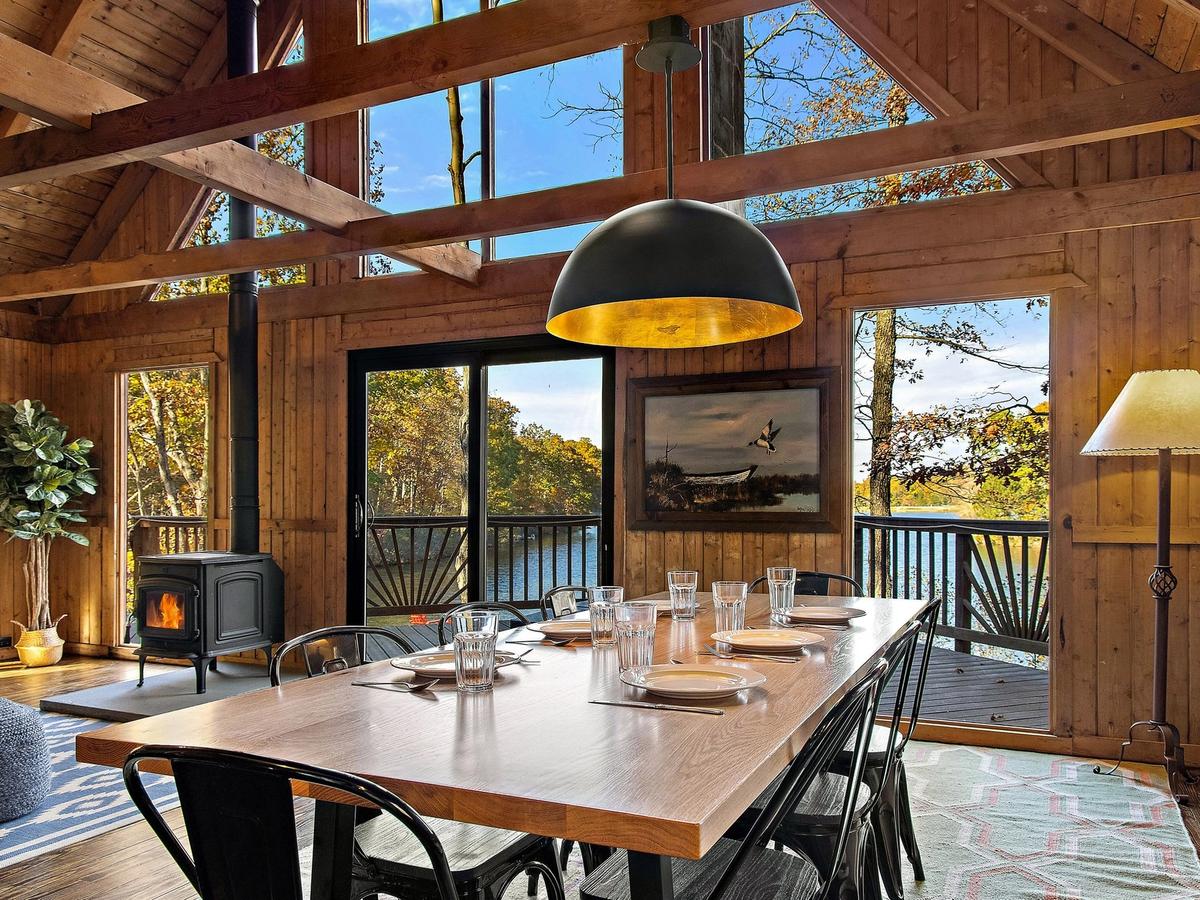 Interior of dining room with windows overlooking the nature and lake with cozy fireplace indoors