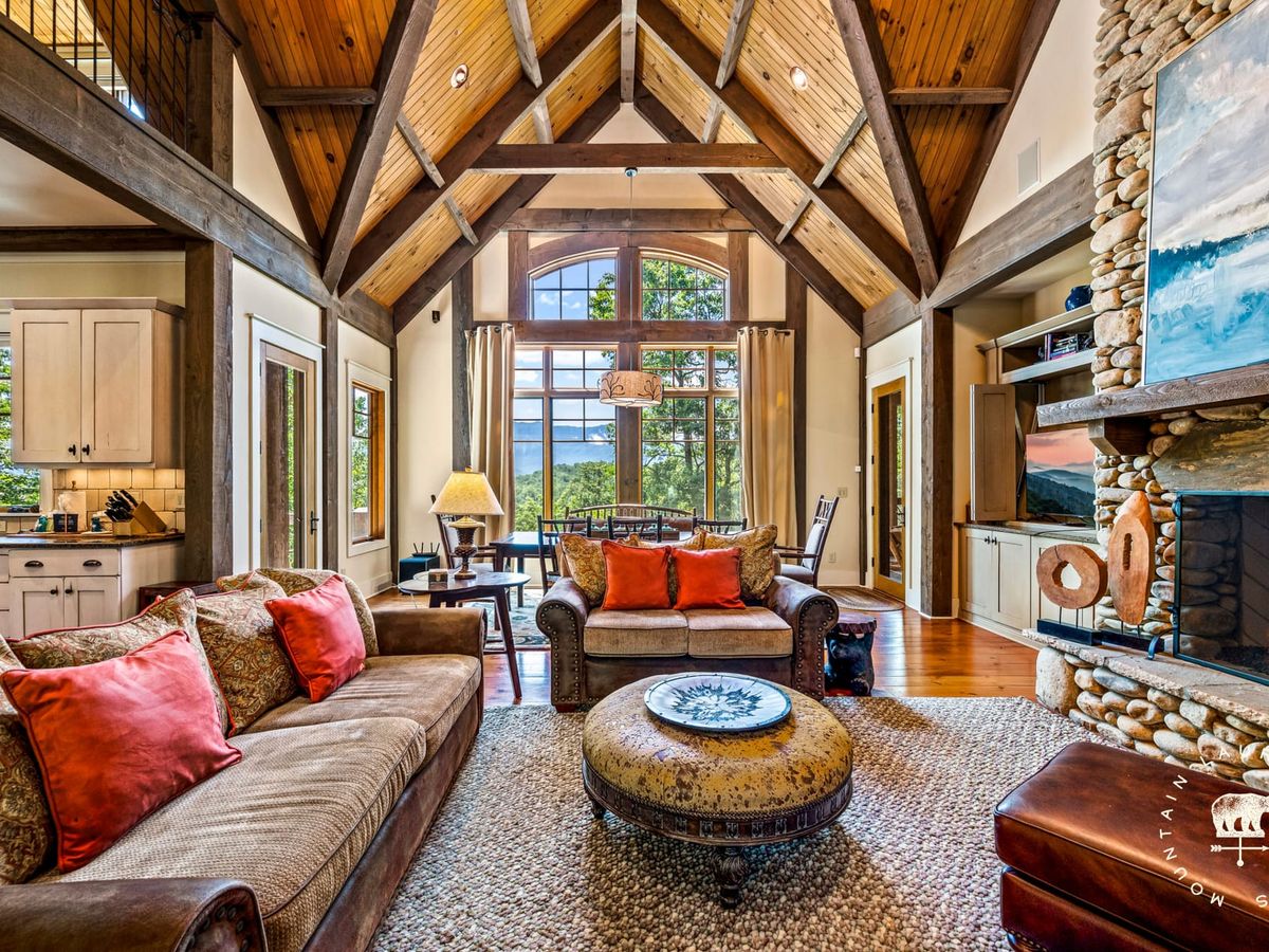 Wood Fern Lodge near Gatlinburg has clean, modern design with a glass dining table, tall ceilings, and forest views. It’s a peaceful retreat with a hot tub and game room.