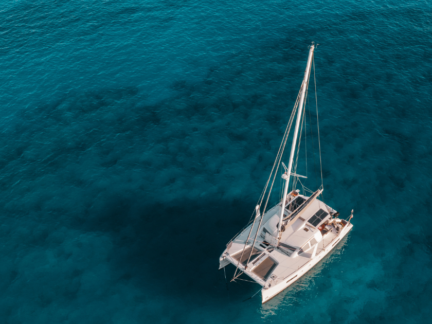 A white catamaran floats in deep blue ocean waters, ready for a day of sailing or fishing adventures off the Hawaiian coast. The calm sea stretches endlessly, perfect for boat lovers.