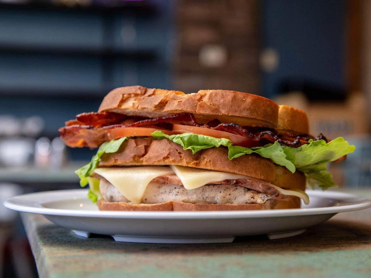 A thick sandwich layered with grilled chicken, melted cheese, lettuce, tomato, and crispy bacon on toasted bread. This hearty café favorite is perfect for a satisfying lunch.