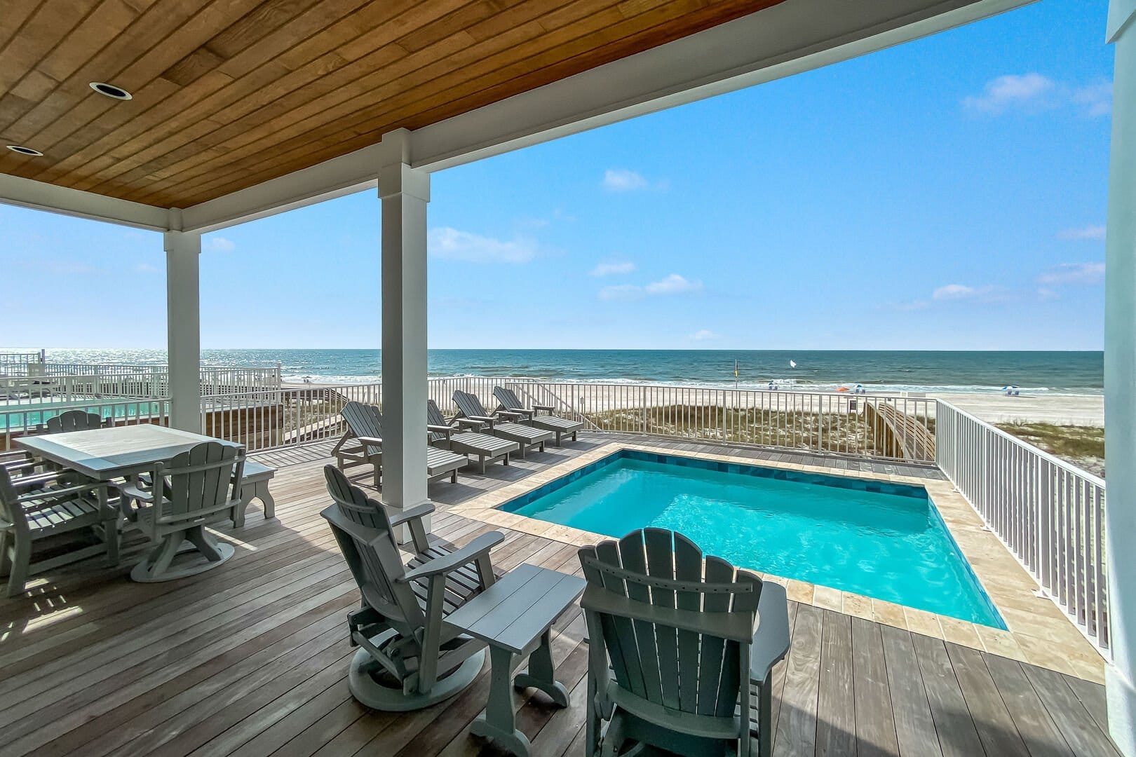 An oceanfront home with a private pool, lounge chairs, and wide-open Gulf views. The wood deck and bright blue waters create a picture-perfect setting for beach days and sunset evenings.
