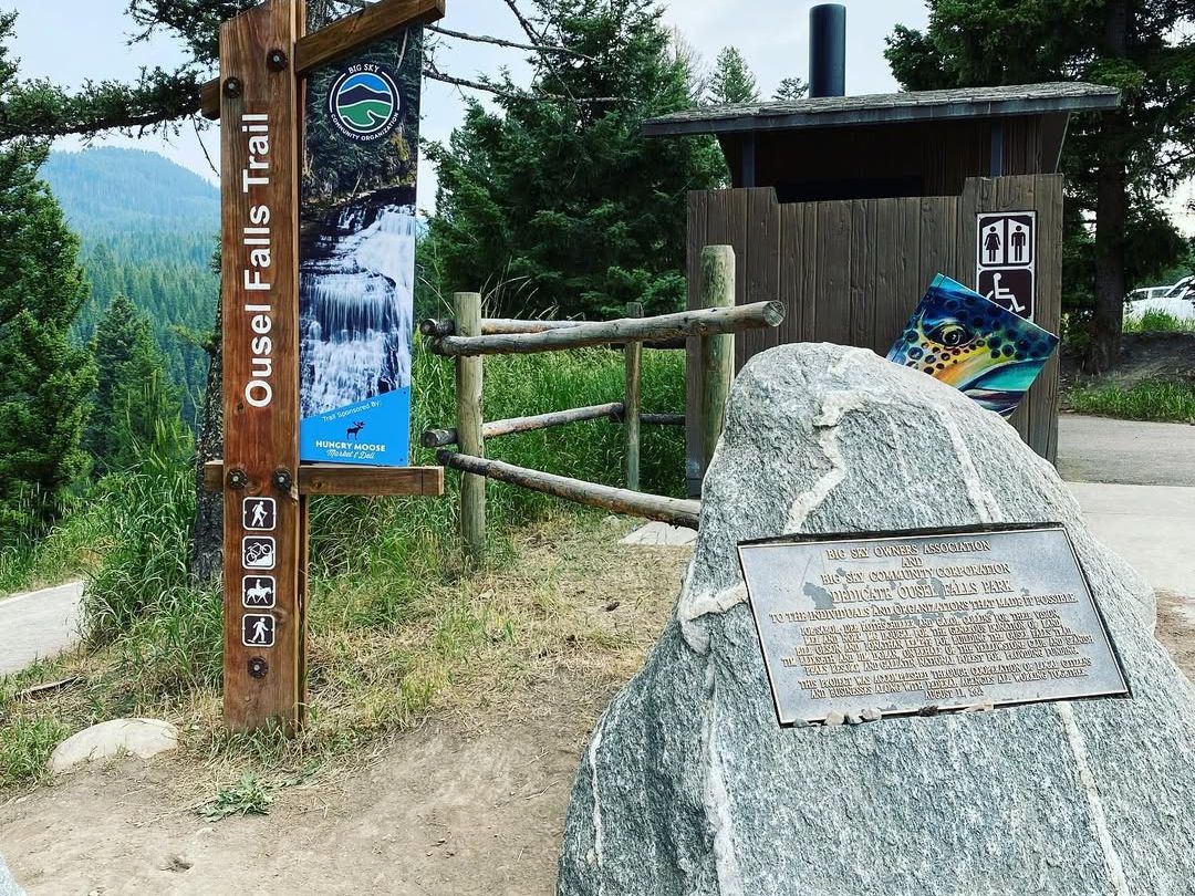 Trailhead sign for Ousel Falls Road in Big Sky, Montana, surrounded by forest views. A popular starting point for hikers exploring one of the area’s most scenic waterfalls.