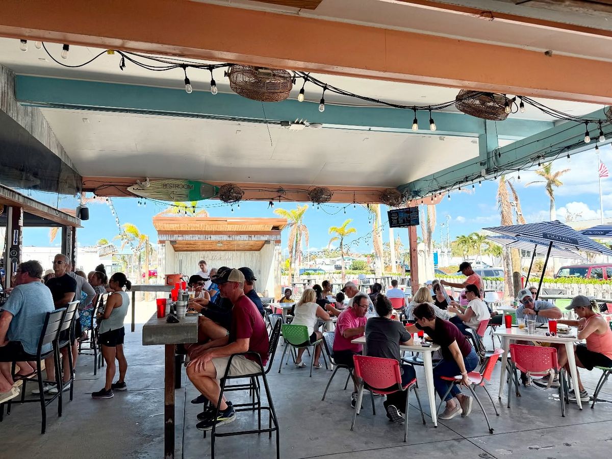 Guests enjoy casual outdoor dining at The Ugly Grouper, a popular waterfront restaurant near the marina. The open-air seating, string lights, and relaxed crowd create a fun beach-town vibe. This spot is well known for fresh seafood, drinks, and laid-back coastal dining.