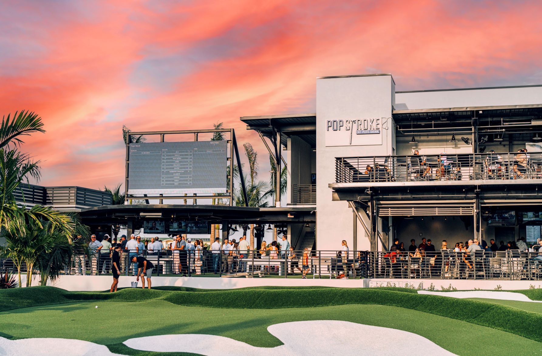 PopStroke Sarasota comes alive at sunset with people enjoying mini golf, drinks, and food on the outdoor course. This popular Sarasota spot mixes entertainment, social vibes, and great views for a fun night out.