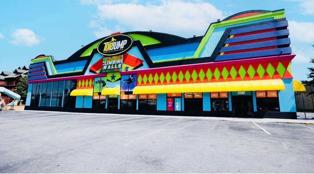 A bright, colorful building houses TopJump Trampoline and Extreme Arena in Pigeon Forge. Inside, visitors can enjoy climbing walls, trampolines, and family-friendly attractions for all ages.