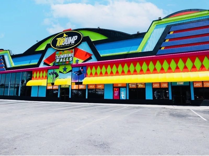 A bright, colorful building houses TopJump Trampoline and Extreme Arena in Pigeon Forge. Inside, visitors can enjoy climbing walls, trampolines, and family-friendly attractions for all ages.
