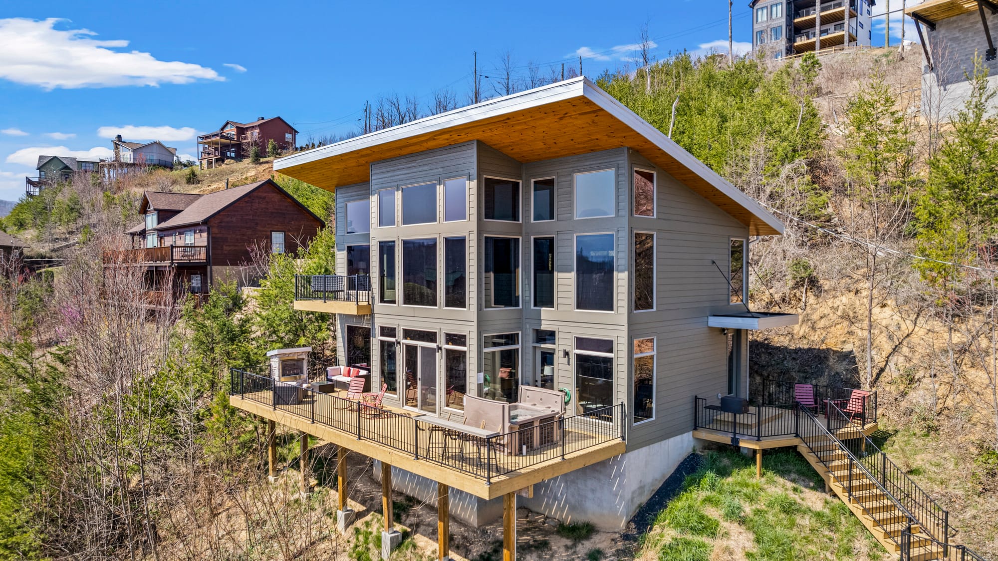 A modern mountain cabin in Gatlinburg, Tennessee, surrounded by wooded hills and panoramic views. Expansive windows and wraparound decks let guests soak in the natural beauty.