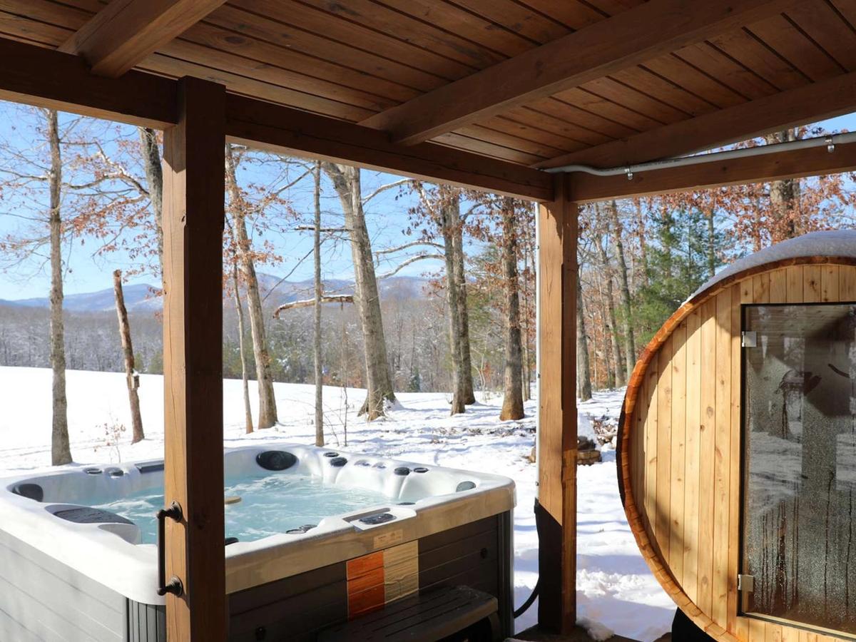 Private hot tub and sauna side by side underneath balcony with snow in the background