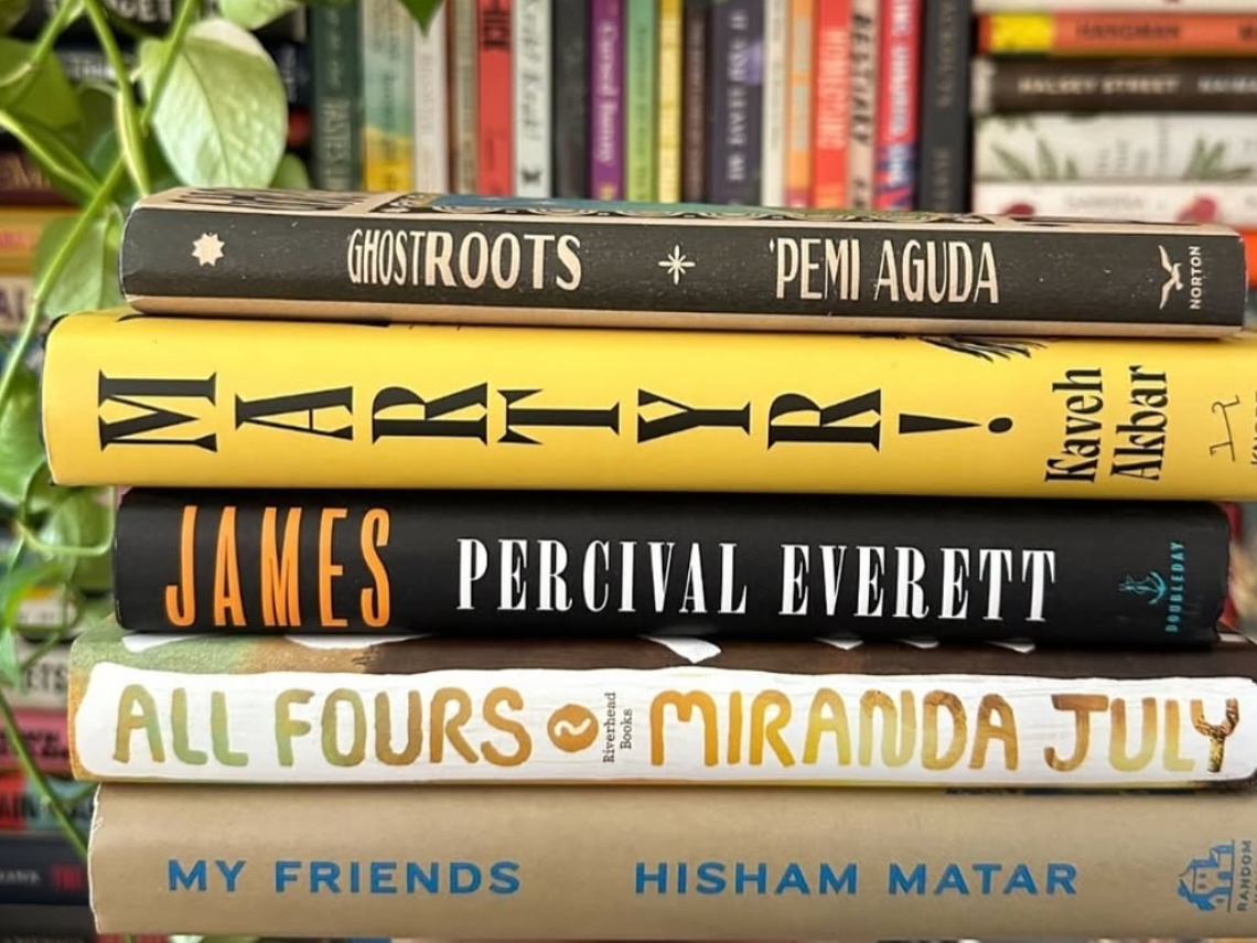 Stack of books on white hands with books in the background