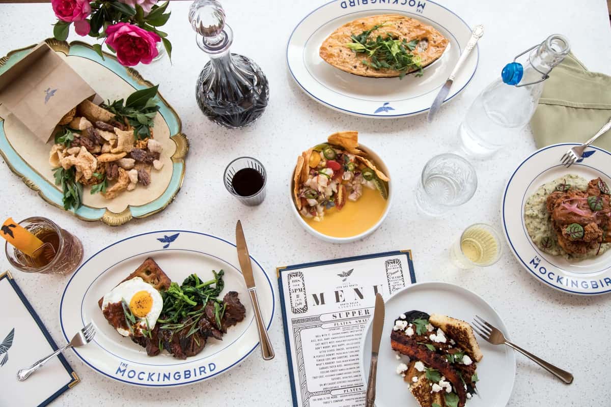 An artful table spread with gourmet dishes, colorful sides, and elegant plating. The mix of textures and fresh ingredients highlights the restaurant’s creative approach to modern American cuisine.