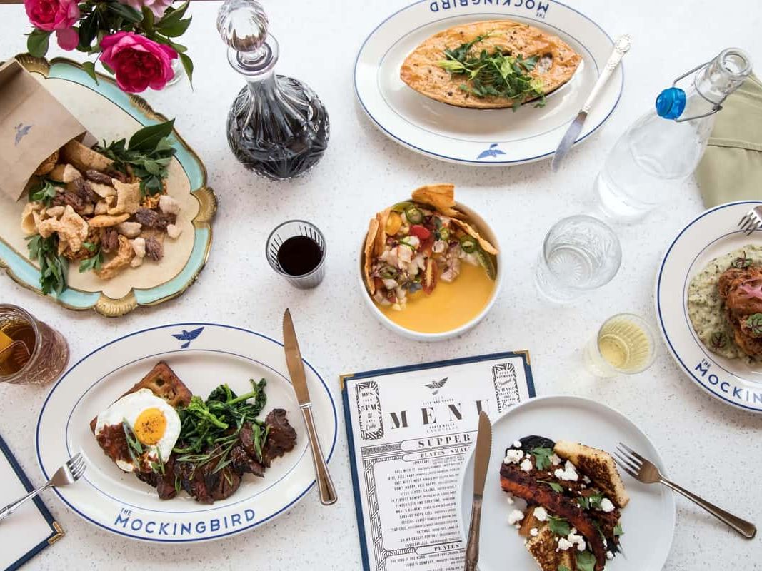 An artful table spread with gourmet dishes, colorful sides, and elegant plating. The mix of textures and fresh ingredients highlights the restaurant’s creative approach to modern American cuisine.