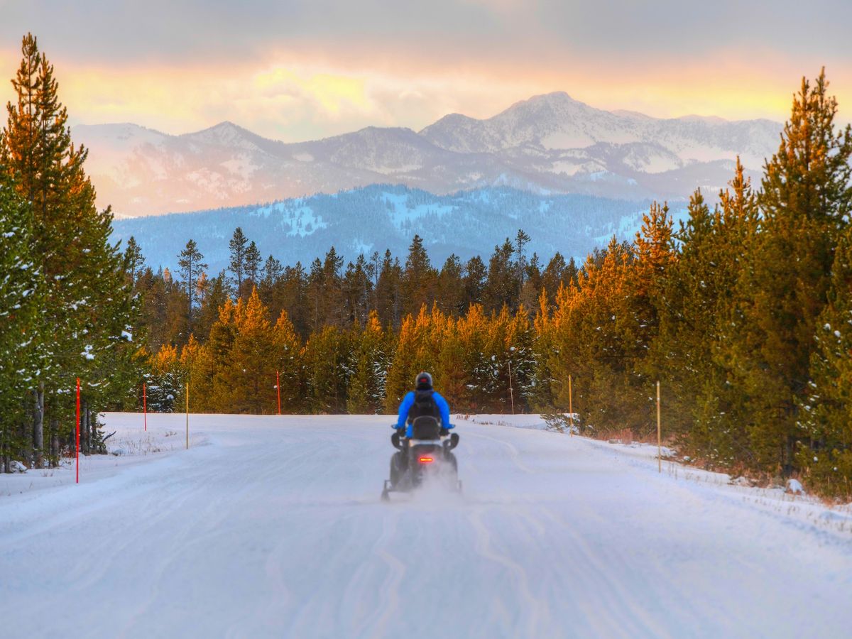 Single Snowmobile Rider on Trail in West Yellowstone, MT at Sunset