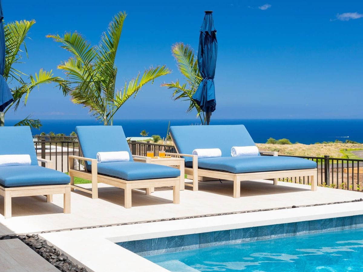 Three blue lounge chairs side by side with private pool in front and gate surrounding area