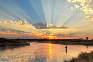 View of a Person Fly Fishing in a West Yellowstone River At Sunset