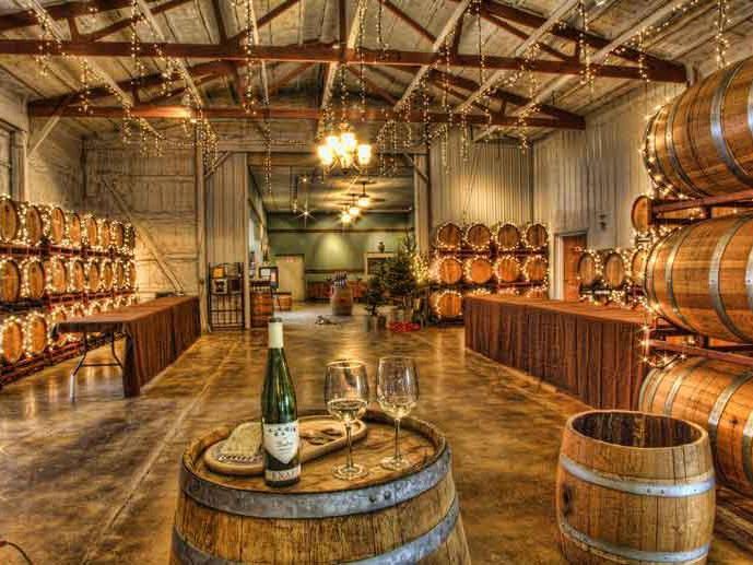 A cozy wine cellar setup at FLX Summer Fest with wooden barrels, string lights, and wine glasses ready for tasting. Events like this highlight the Finger Lakes’ strong wine culture and relaxed social vibe.