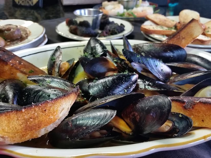 A bowl of steamed mussels in broth, served with toasted garlic bread on the side. The Library offers fine dining in Myrtle Beach with elegant seafood dishes like this.