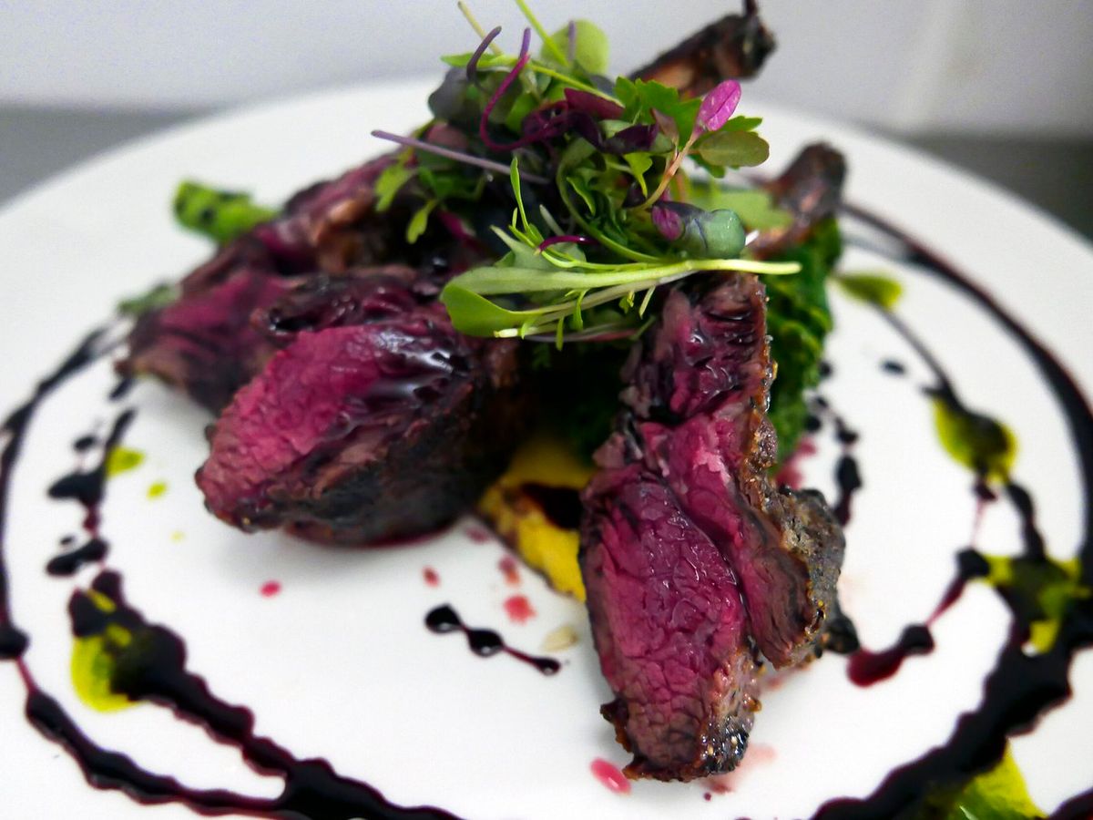 A plate of tender, artfully plated lamb chops drizzled with balsamic reduction at Michaelangelo’s Big Sky. A refined Italian dining experience in the heart of Montana.