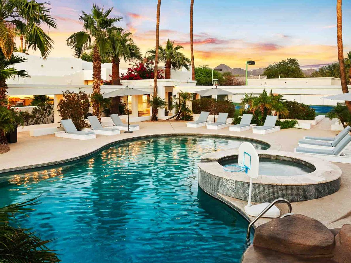 Large private pool and spa at a modern luxury estate surrounded by palm trees, lounge chairs, and mountain views at sunset. This outdoor space feels like a private resort, perfect for swimming, sunbathing, and group getaways.