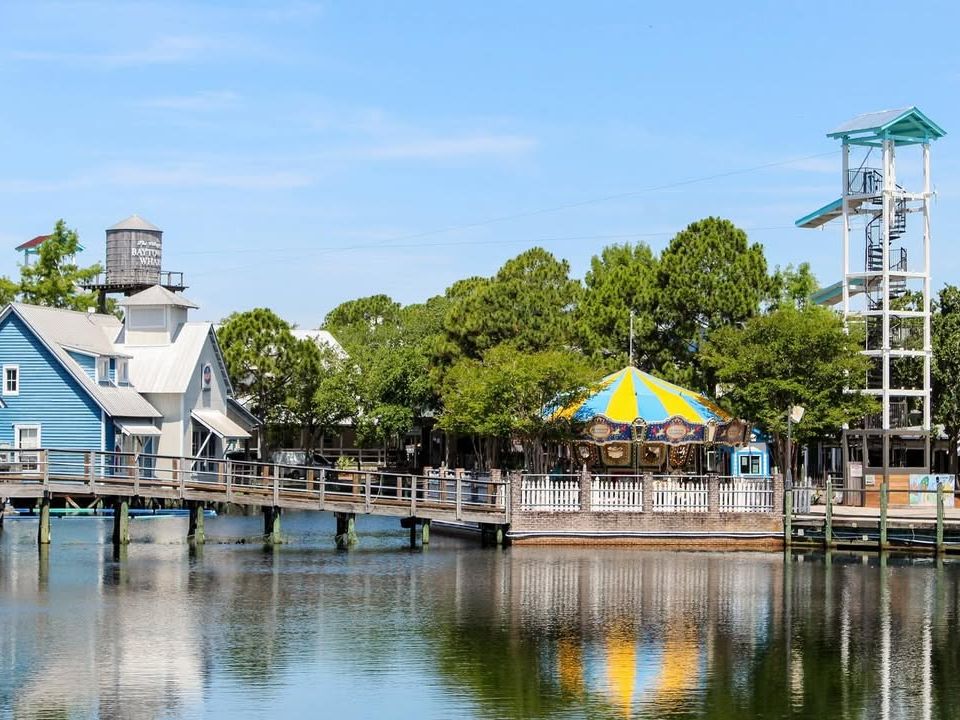 Baytowne Wharf features colorful coastal buildings and a cheerful carousel by the water. A wooden boardwalk leads visitors through this lively village filled with shops, rides, and family activities.