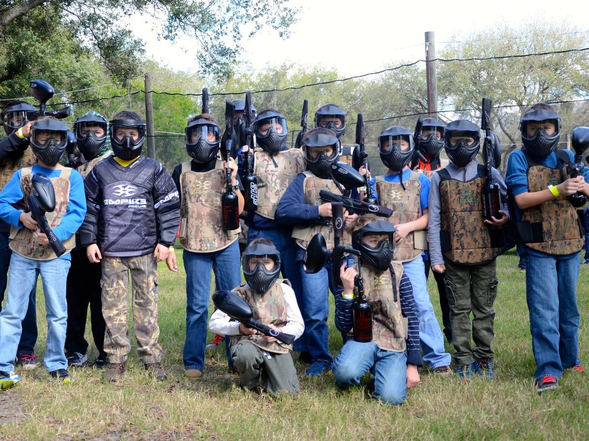 A group of kids geared up in helmets and camouflage vests prepare for an exciting paintball match at Outdoor Xtreme. The outdoor field is perfect for fun, teamwork, and adventure.